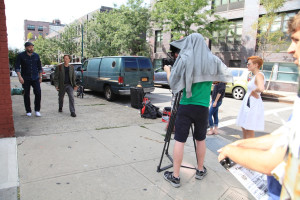 Photographer Andrew Trost hides under his sweatshirt to see despite the Brooklyn glare.
